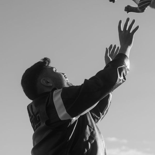 Person standing outdoors with arms raised, feeling energetic.